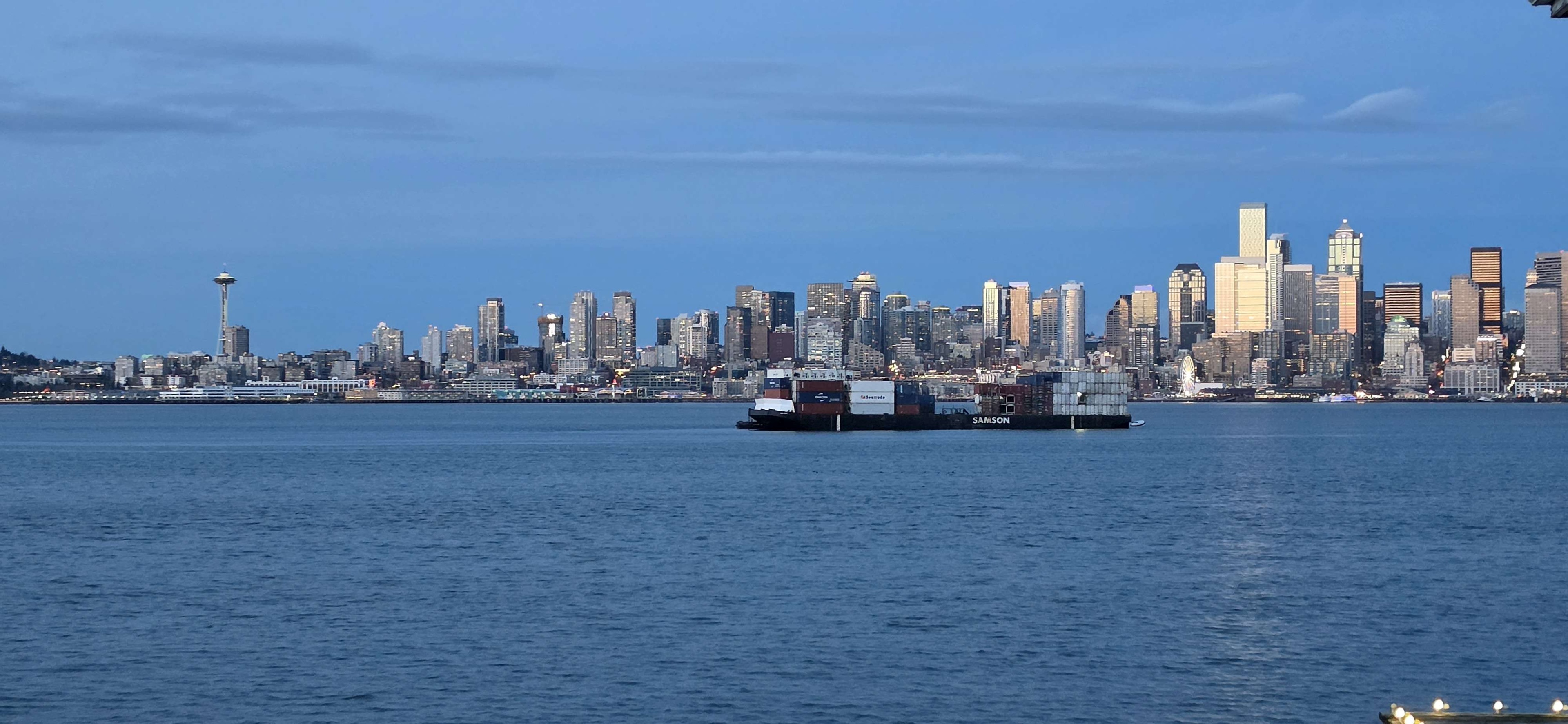 The Seattle skyline across the water with a container ship passing